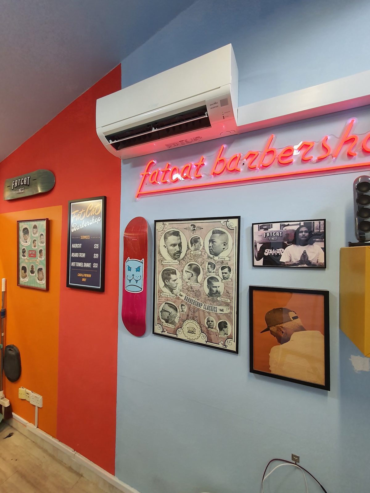 The orange wall with framed barber prints and neon