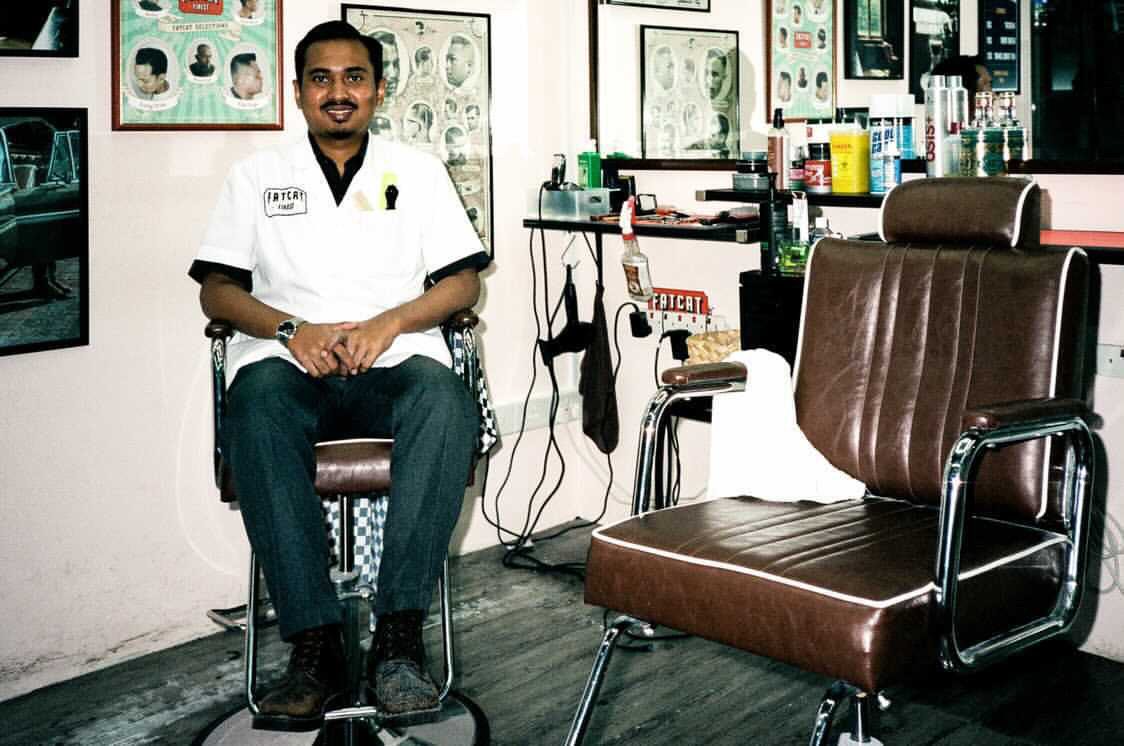 A barber seated in a vintage leather barber chair